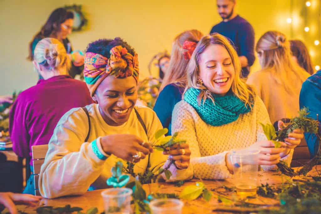 Two friends laugh whilst taking part in a wreath making workshop at Winter Wildfire.